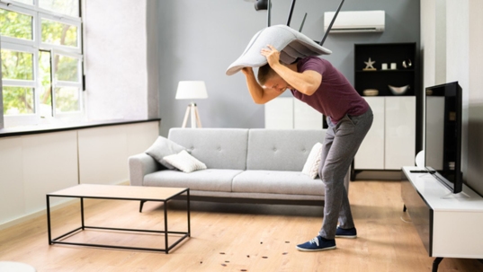 man in an apartment hitting bugs with chair